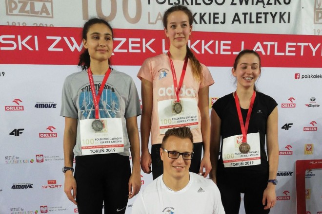 Kornelia Sura na najwyższym stopniu podium. Poniżej trener Tomasz Saska