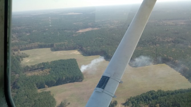 Leśnicy w ochronie lasów wykorzystują m.in.: samoloty. Widok na pogorzelisko w lesie z pokładu samolotu.
